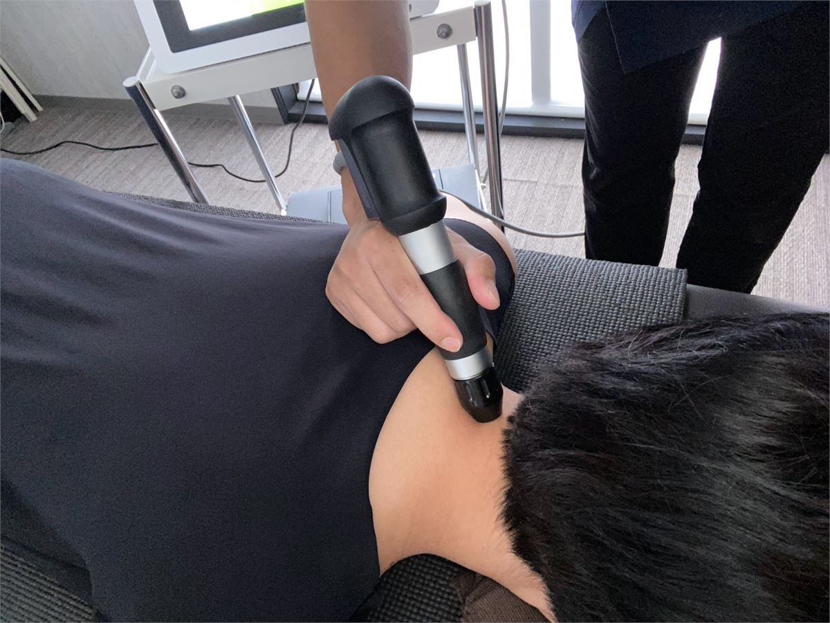 肩・首まわりへショックマスターの圧力波を照射している施術のようす