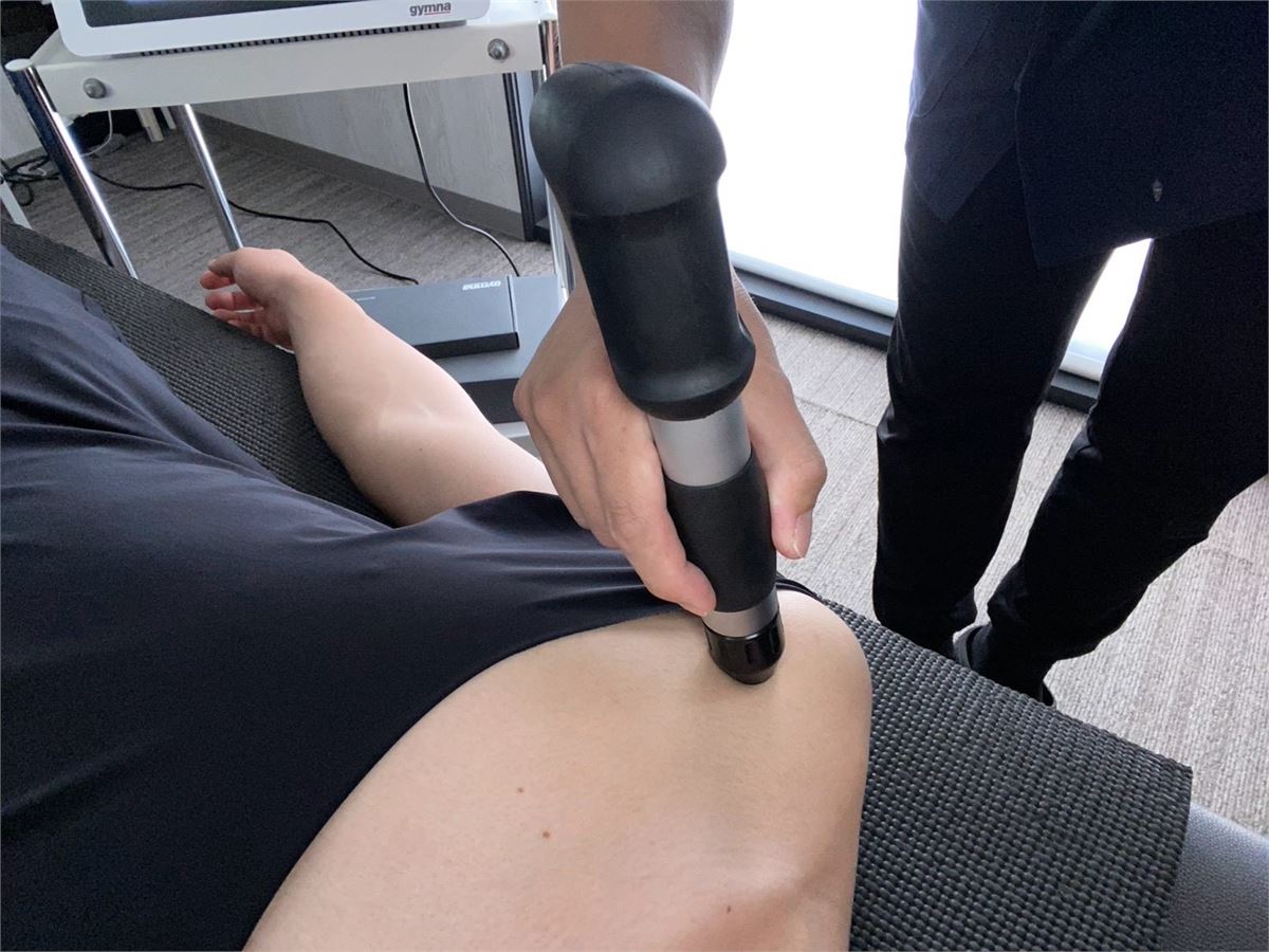 ショックマスターのプローブを太もも・膝上に当てて圧力波を照射している施術のようす